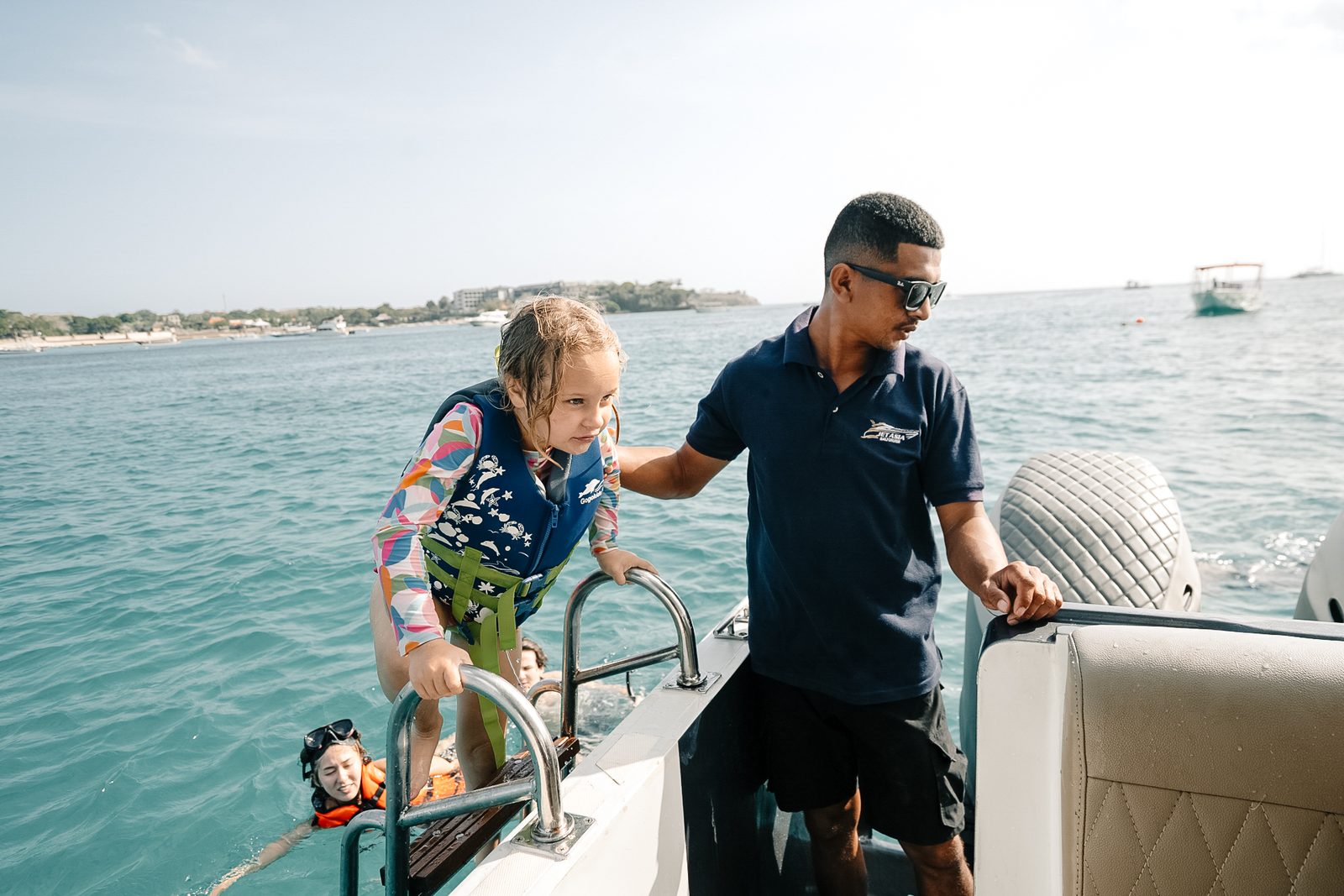 Yacht crew assisting a young guest on deck during a Bali charter