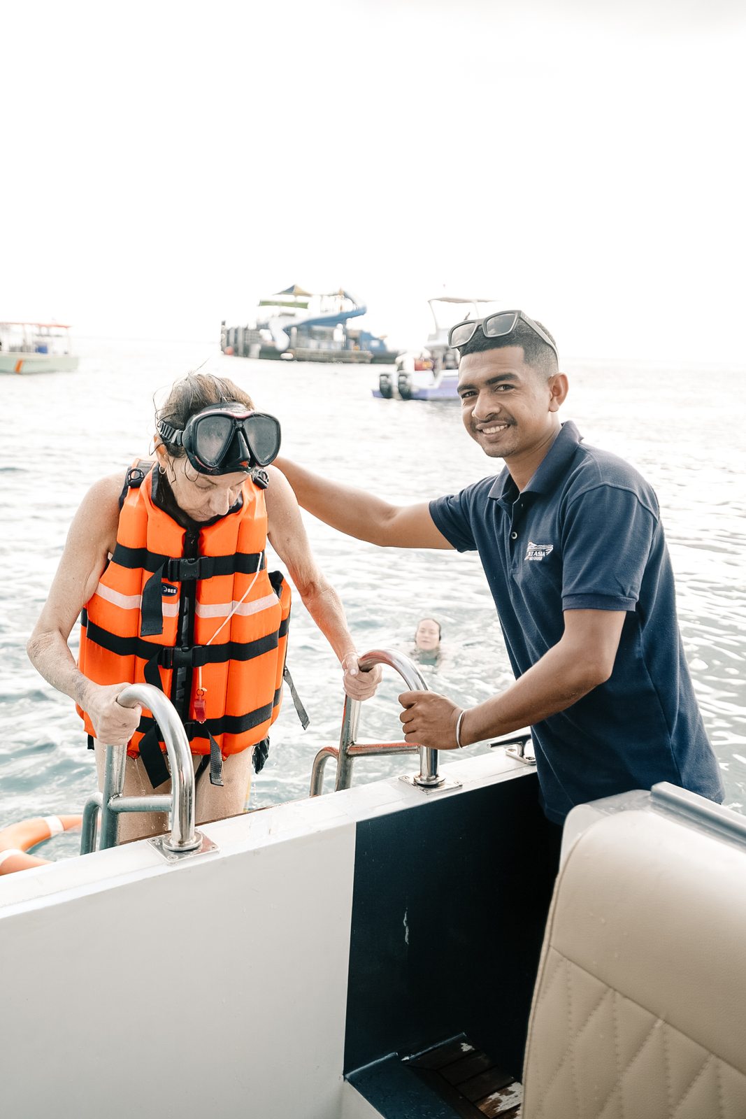Crew helping a guest with a snorkeling mask aboard the yacht