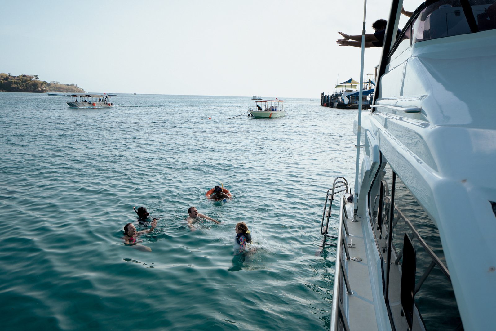 Guests swimming beside the yacht with island views in Bali